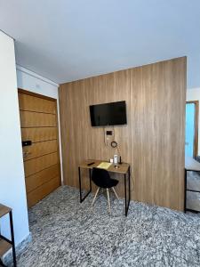 Habitación con escritorio y TV en la pared. en LK Lourdes, en Belo Horizonte