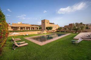 a courtyard with a swimming pool and chairs and a building at Tigmi in Marrakech