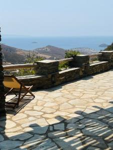 a stone wall with a bench and a chair on a patio at Anastasia Luxury Villas in Gavrio