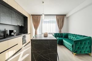 a living room with a green couch and a kitchen at FLH - Robella Apartment in Sibiu