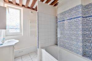 a white bathroom with a tub and a sink at Appartement quartier Vaugueux in Caen