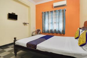 a bedroom with a bed with an orange wall at SPOT ON New Balaji Residency in Hyderabad