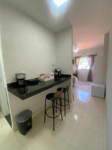 a kitchen and living room with a counter and stools at MAHALO 1004 Suites in Maricá
