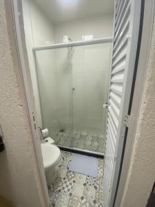 a bathroom with a toilet and a glass shower at MAHALO 1004 Suites in Maricá