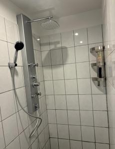 a shower in a bathroom with white tiles at Apartment nah Flughafen, Messe, Arena, Dome in Düsseldorf