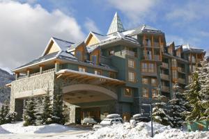 a large building in the snow with a car parked in front at Renovated 1Bed-1Bath in Village with Pool, Hot Tub, and Sauna in Whistler