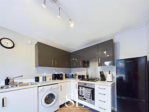 a kitchen with white cabinets and a black refrigerator at Modern 3 bed Willenhall House in Willenhall