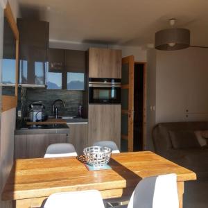 eine Küche mit einem Holztisch und weißen Stühlen in der Unterkunft Appartement entièrement rénové, vue exceptionnelle in Huez