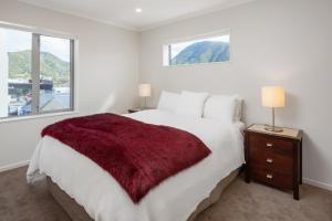 a bedroom with a large bed with a red blanket on it at Oxleys 406 3 bedroom Waterfront Apartment in Picton