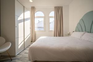 a bedroom with a white bed and two windows at William Martin Apartments in Huelva