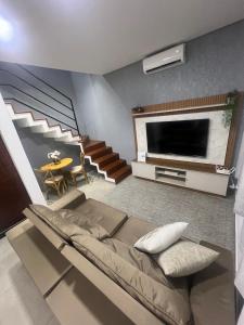 a living room with a couch and a tv and stairs at Sobrado confortavel e central in Foz do Iguaçu