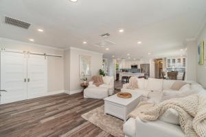 a living room with white furniture and a kitchen at Sailboat access - Under 15 min from Fort Myers Beach - Fire Pit and Heated Pool - Villa Canalview Cove in Fort Myers