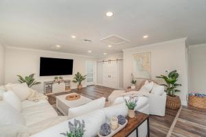 a living room with white furniture and a flat screen tv at Sailboat access - Under 15 min from Fort Myers Beach - Fire Pit and Heated Pool - Villa Canalview Cove in Fort Myers