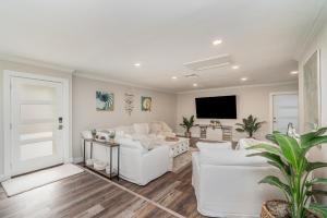 a living room with white furniture and a flat screen tv at Sailboat access - Under 15 min from Fort Myers Beach - Fire Pit and Heated Pool - Villa Canalview Cove in Fort Myers