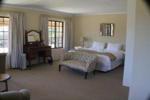1 dormitorio con cama, silla y espejo en Cedar Garden, en Underberg