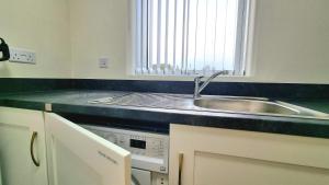 a kitchen with a sink and a counter top at Modern New Build 3-Storey Home with Parking near Leicester City Centre in Leicester +34 photos