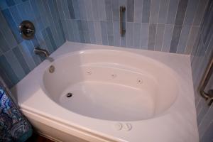 a white bath tub in a bathroom with blue tiles at Peaceful Pine Place Cabin in Pine +23 photos