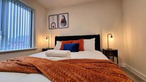 a bedroom with a large bed with orange and blue pillows at Modern New Build 3-Storey Home with Parking near Leicester City Centre in Leicester