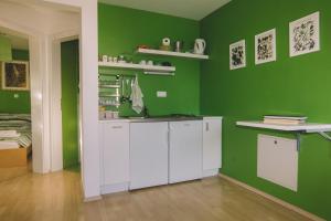 uma cozinha com paredes verdes e armários brancos em Apartments Sasha em Bled