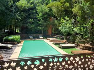 a swimming pool with chaises and benches in a garden at Complejo Aires del Bosque in Chascomús