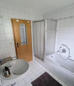 un bagno piastrellato bianco con vasca e doccia. di Moderne und Gemütliche Stadtnahe Wohnung a Hassfurt Altre 21 foto