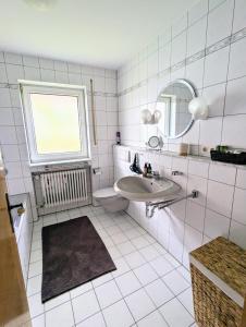 un bagno bianco con lavandino e specchio di Moderne und Gemütliche Stadtnahe Wohnung a Hassfurt