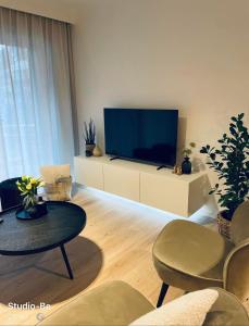 a living room with a tv and a table and chairs at Studio-be in Nieuwpoort