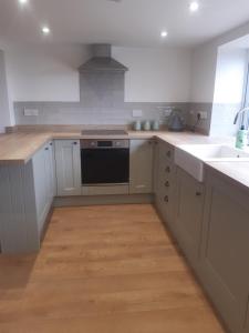 eine Küche mit weißen Schränken und einem schwarzen Geschirrspüler in der Unterkunft Jasmine Cottage in Shrewsbury