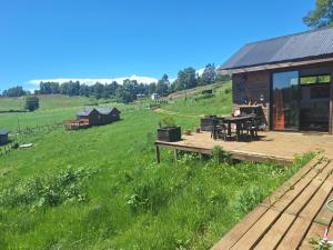 una cabaña en un campo con una terraza de madera en Eco Brújula II, en Villarrica
