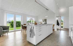 a kitchen with white cabinets and a table and chairs at Amazing Home In Odder With Kitchen in Odder +20 photos