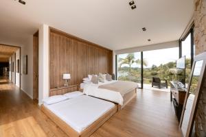 a bedroom with two beds and a large window at Villa al lado de la represa de Guatapé con jacuzzi y cancha de tennis privada in El Peñol +53 photos