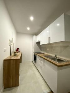 ベルジュラックにあるT2 Cosy proche Centre Villeの白いキャビネットとシンクを備えた広いキッチン