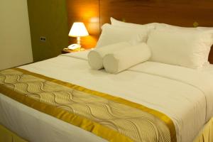 a large bed with white sheets and pillows at Unique Towers Luxury Boutique Suites in Colombo