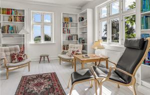 a living room with a table and chairs and bookshelves at 5 Bedroom Nice Home In Svaneke in Svaneke