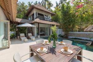 an outdoor dining area with a wooden table and chairs at New Moon in Ubud