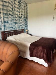 a bedroom with a bed and a leather couch at Proa Amarilla in Punta del Este