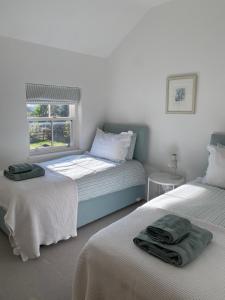 a bedroom with two beds and a window at Grooms Cottage by Sheriff Hutton Castle near York in Sheriff Hutton