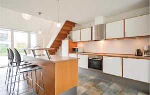 a kitchen with white cabinets and a bar with stools at Two-Bedroom Holiday Home In Romo in Sønderby