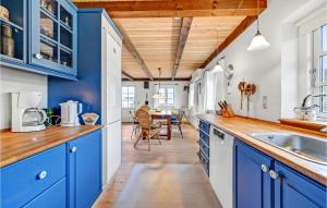a kitchen with blue cabinets and a dining room at Holiday Home Rauhesvej Hvide Sande in Bjerregård