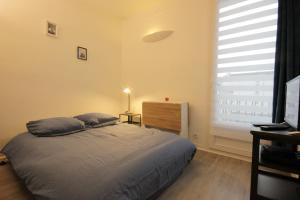a bedroom with a bed and a desk and a window at Studio Maurepas centre-ville in Maurepas