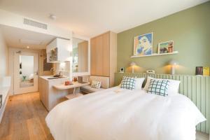 a bedroom with a large white bed and a kitchen at Bikube Coliving Hôtel - Lyon Centre Lumière in Lyon