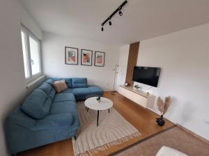 クープレスにあるApartman Mikaの青いソファとテーブルのあるリビングルーム
