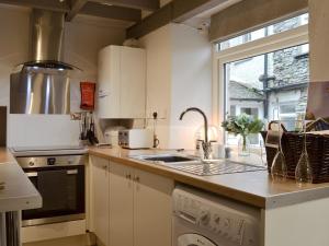 a kitchen with white cabinets and a sink and a window at Grange End Stables in Grasmere