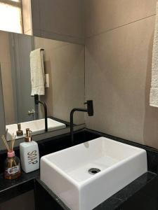 a bathroom with a white sink and a mirror at Apartamento no centro de Uberlândia in Uberlândia