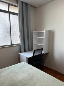 a bedroom with a desk and a chair next to a window at Apartamento no centro de Uberlândia in Uberlândia