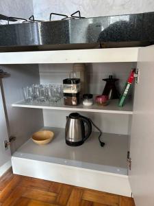 a kitchen shelf with a tea kettle and glasses at Apartamento no centro de Uberlândia in Uberlândia +13 photos
