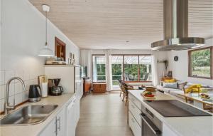 eine Küche mit weißen Arbeitsplatten und einem großen Fenster in der Unterkunft 3 Bedroom Beautiful Home In Nexø in Neksø
