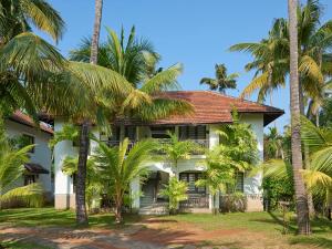 una casa bianca con palme di fronte di Club Mahindra Cherai Beach a Cherai Beach