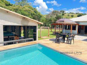 una casa con piscina y una mesa con sombrilla en Chácara próximo à São Lourenço, en Dom Viçoso