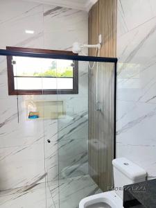 Un baño con ducha de cristal y un inodoro. en Chácara próximo à São Lourenço, en Dom Viçoso